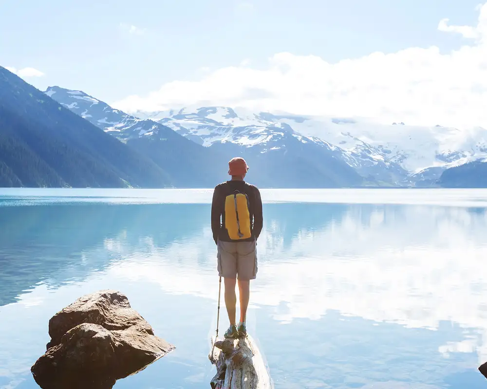 A man standing on the shore of a lake in Garibaldi Lake