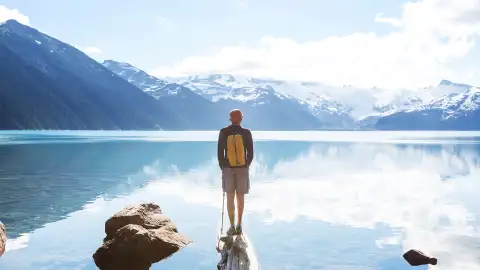 A man standing on the shore of a lake in Garibaldi Lake