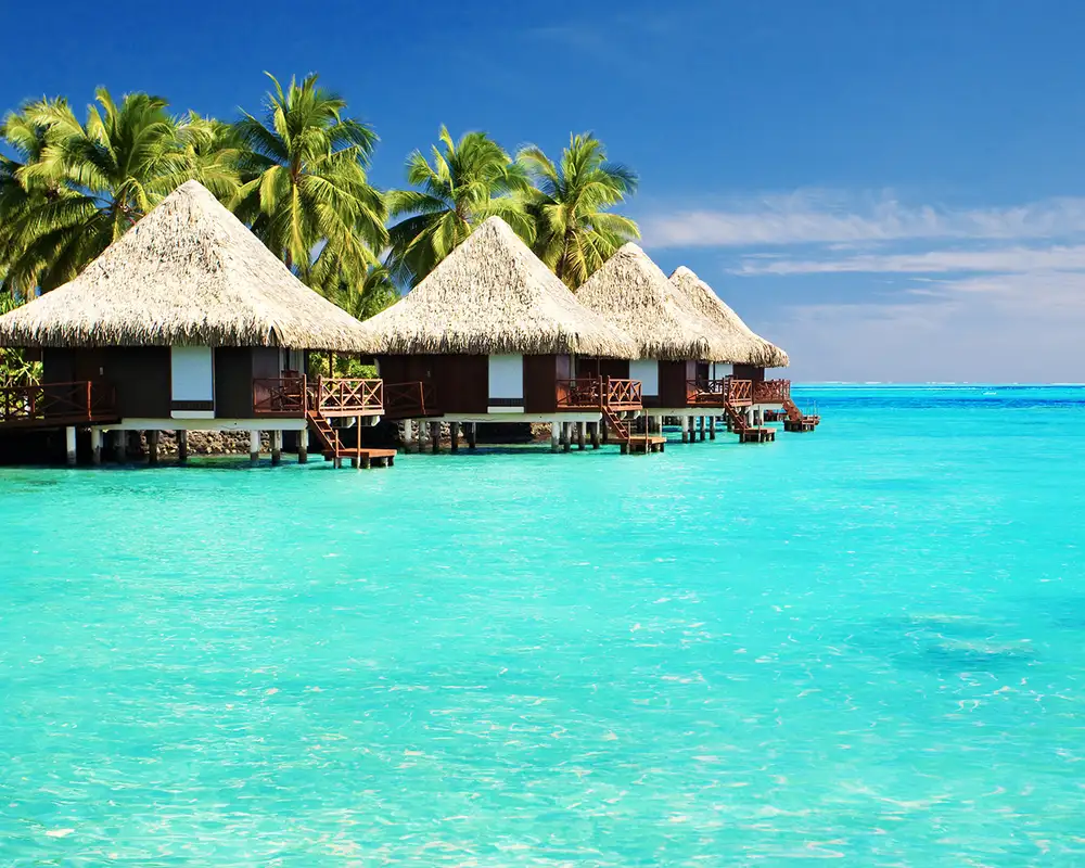 Three huts on the shore surrounded by crystal clear blue water