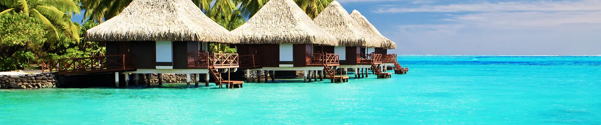 Three huts on the shore surrounded by crystal clear blue water