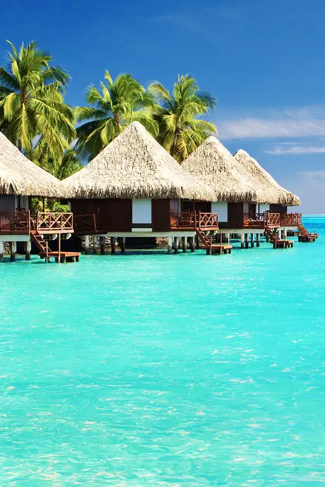 Three huts on the shore surrounded by crystal clear blue water