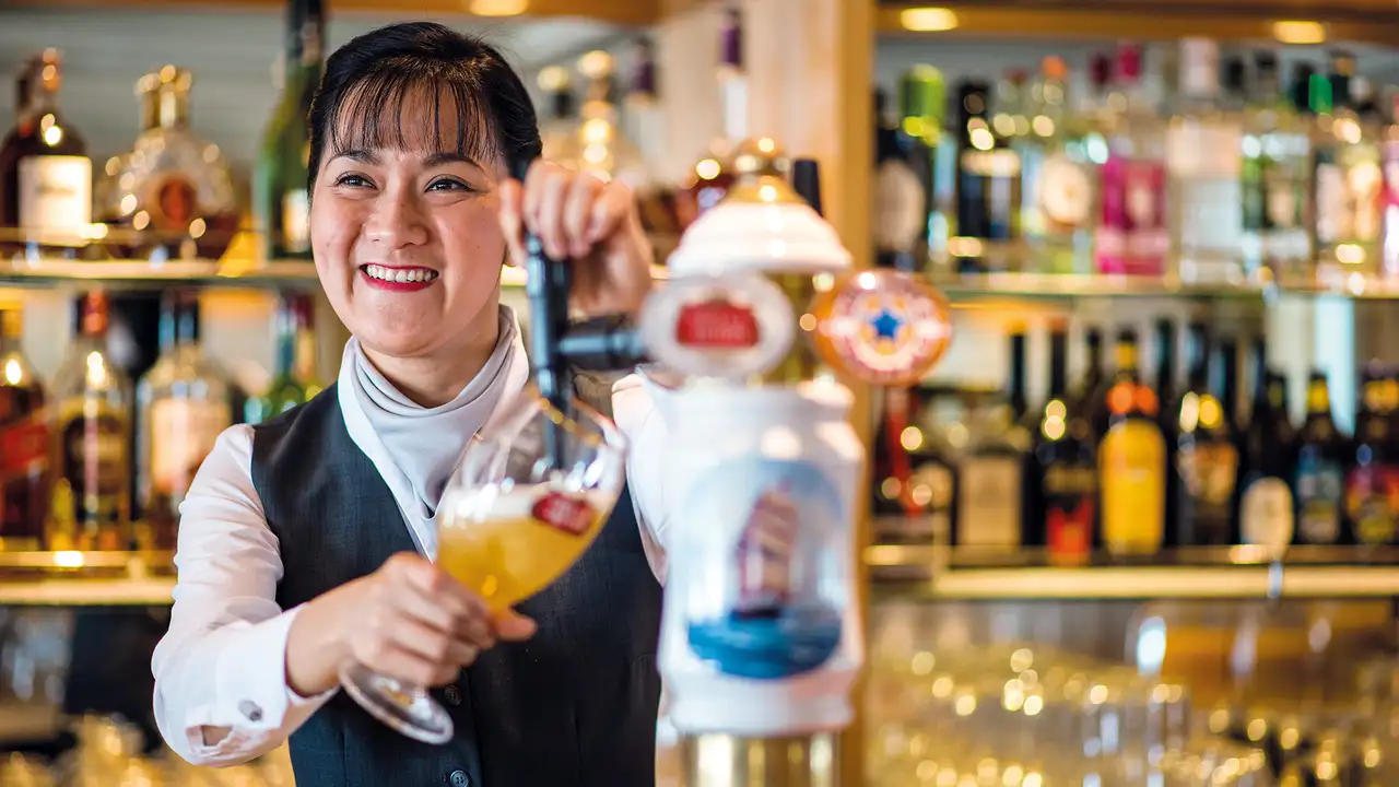 A bartender pouring a drink on a Fred Olsen Ship