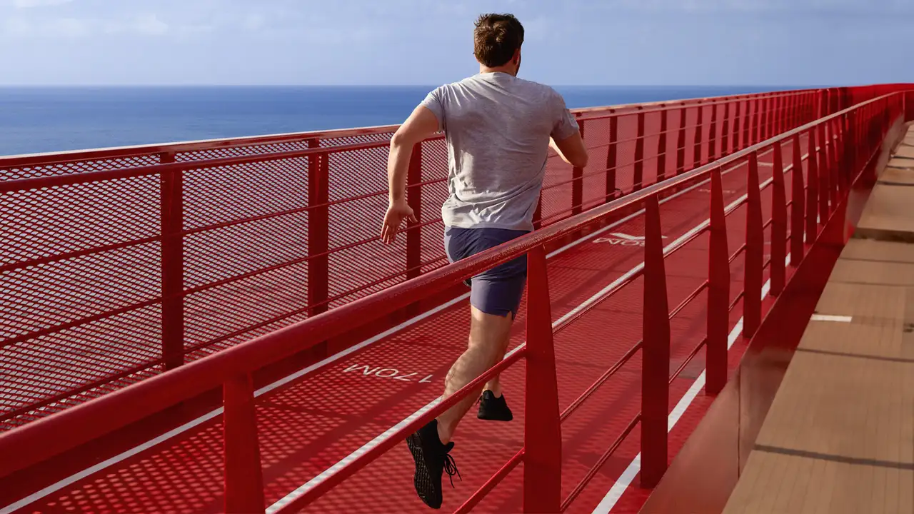 A Man running on a Running track on a Virgin Voyages Ship