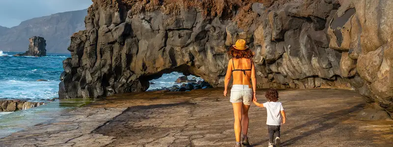 A mother and child walking down a rocky shore of an Island in the canaries