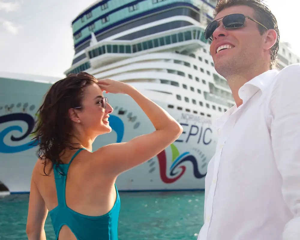 A Couple standing on the docks next to the Norwegian Epic