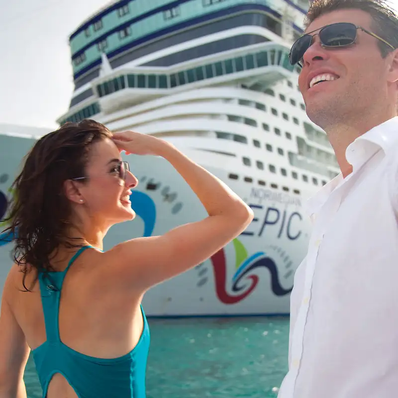 A Couple standing on the docks next to the Norwegian Epic