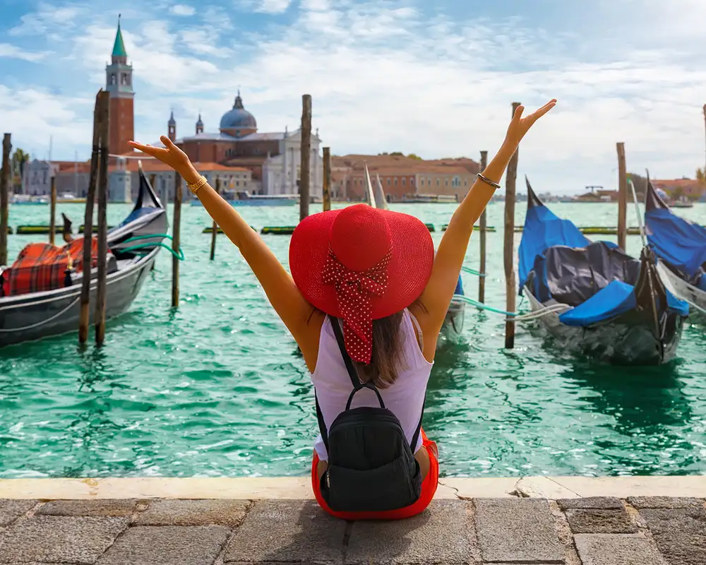A Woman sitting infront of docked gondolas in Venice