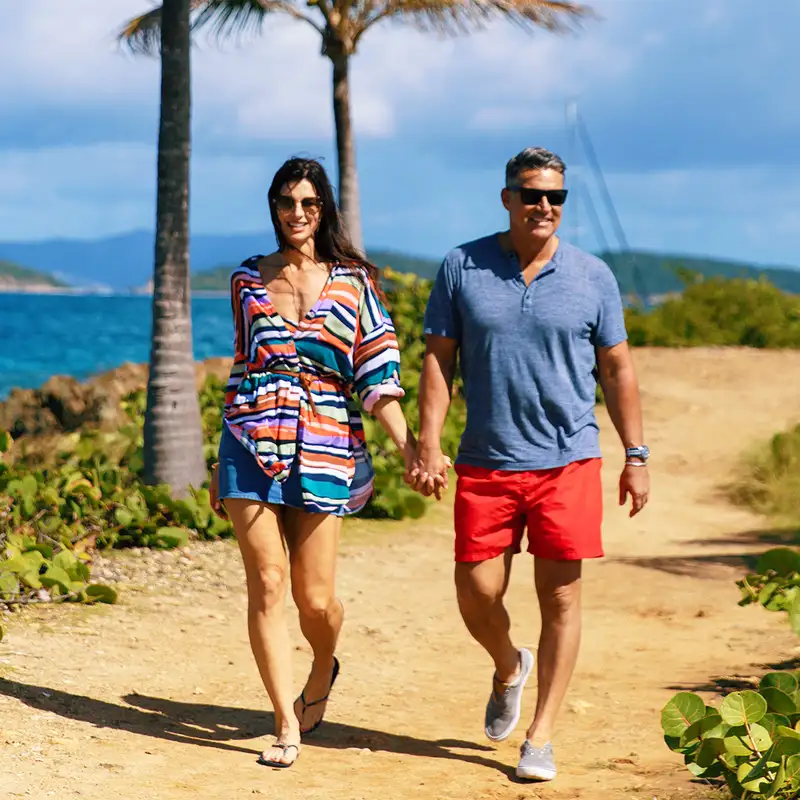A couple walking down a beach path on an Azamara Holiday