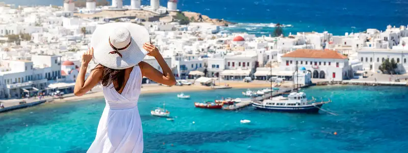 A woman wearing a white dress standing over a Mediterranean town