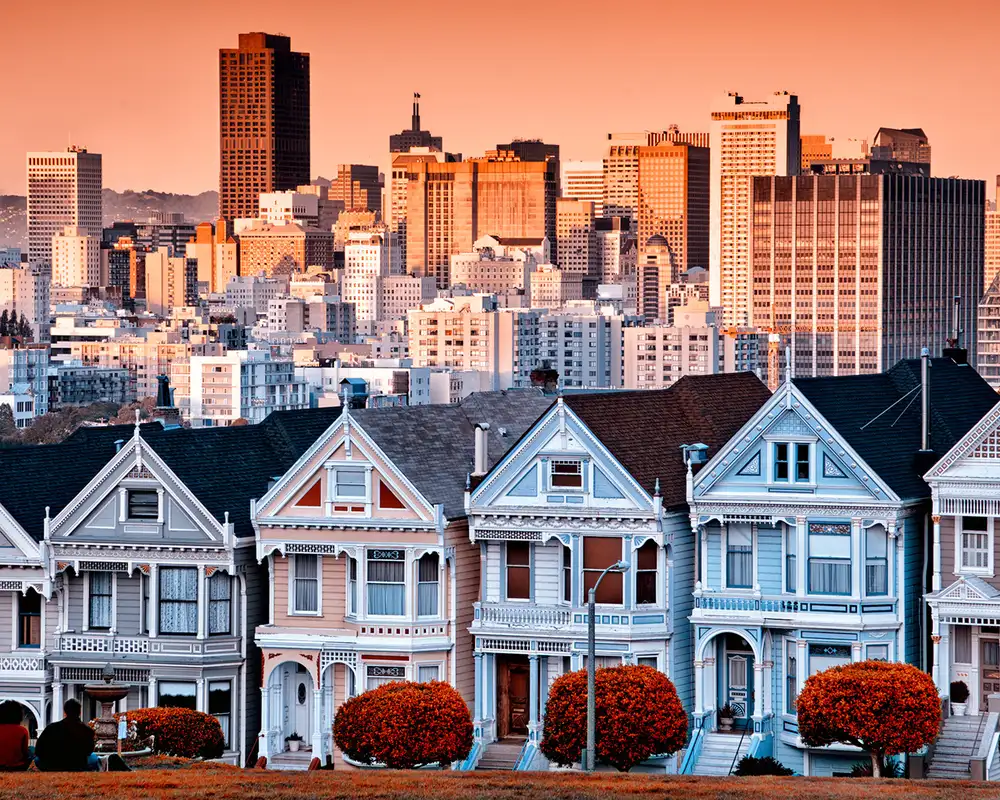 A row of houses with the skyline of San Francisco behind them