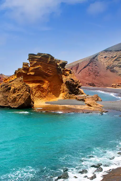 A rocky beach in the Canary Islands with a rock formation in the water