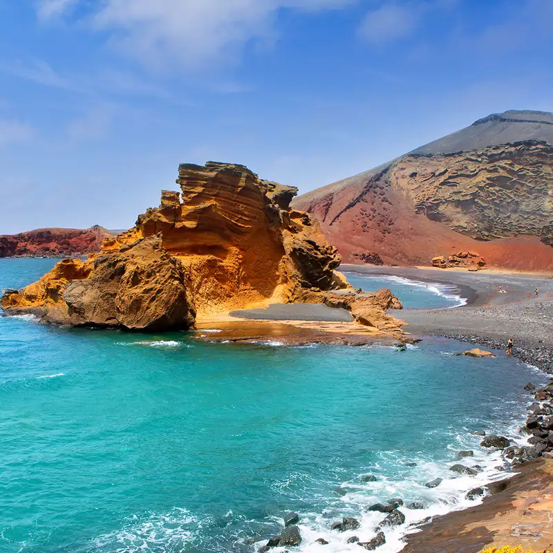 A rocky beach in the Canary Islands with a rock formation in the water