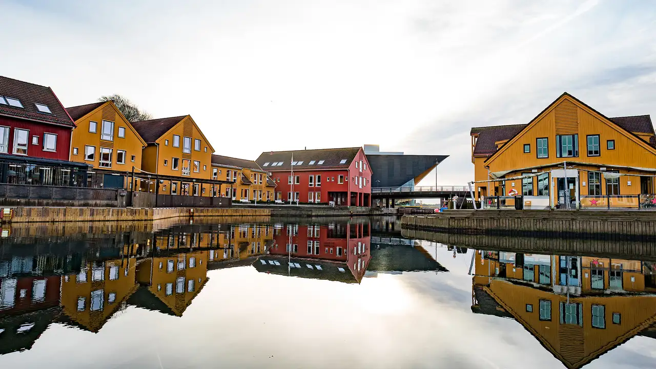 An Image of multiple Yellow and Red Buildings on the riverside of Kristiansand, Norway