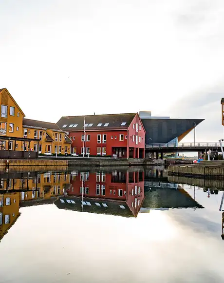 An Image of multiple Yellow and Red Buildings on the riverside of Kristiansand, Norway