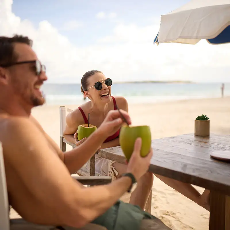 A Couple enjoying drinks on a beach in St Maarten on a Celebrity Cruises Holiday