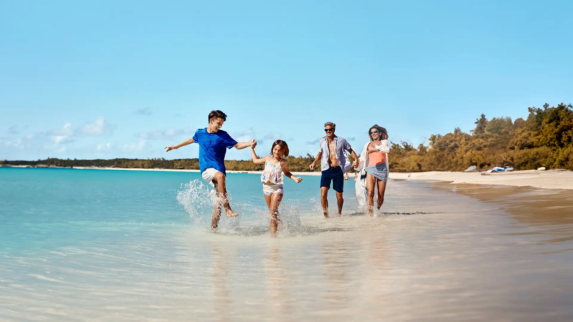 A family walking down the shore of Half Moon Cay
