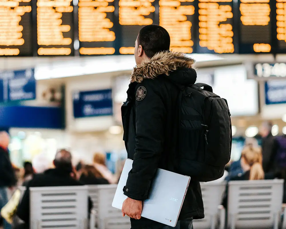A Person standing in an Airport looking at the departure screens