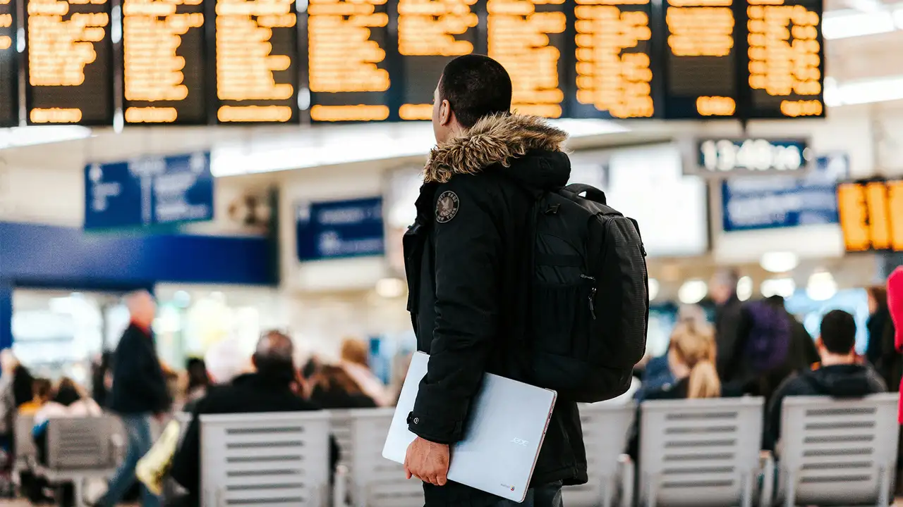 A Person standing in an Airport looking at the departure screens