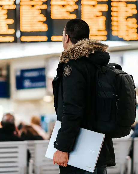 A Person standing in an Airport looking at the departure screens