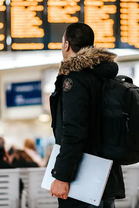 A Person standing in an Airport looking at the departure screens