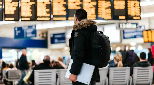 A Person standing in an Airport looking at the departure screens