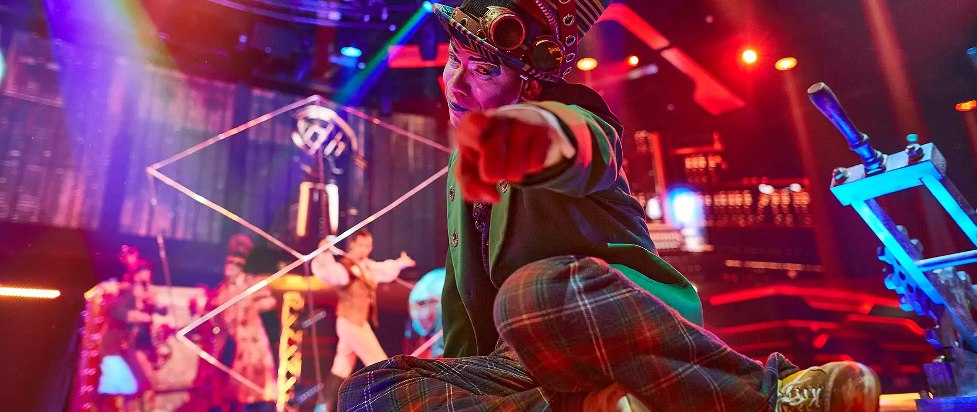 A stage show with a performer pointing at the camera as the rest of the cast are singing and dancing in the background