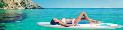 A woman lay on a surfboard floating in blue water