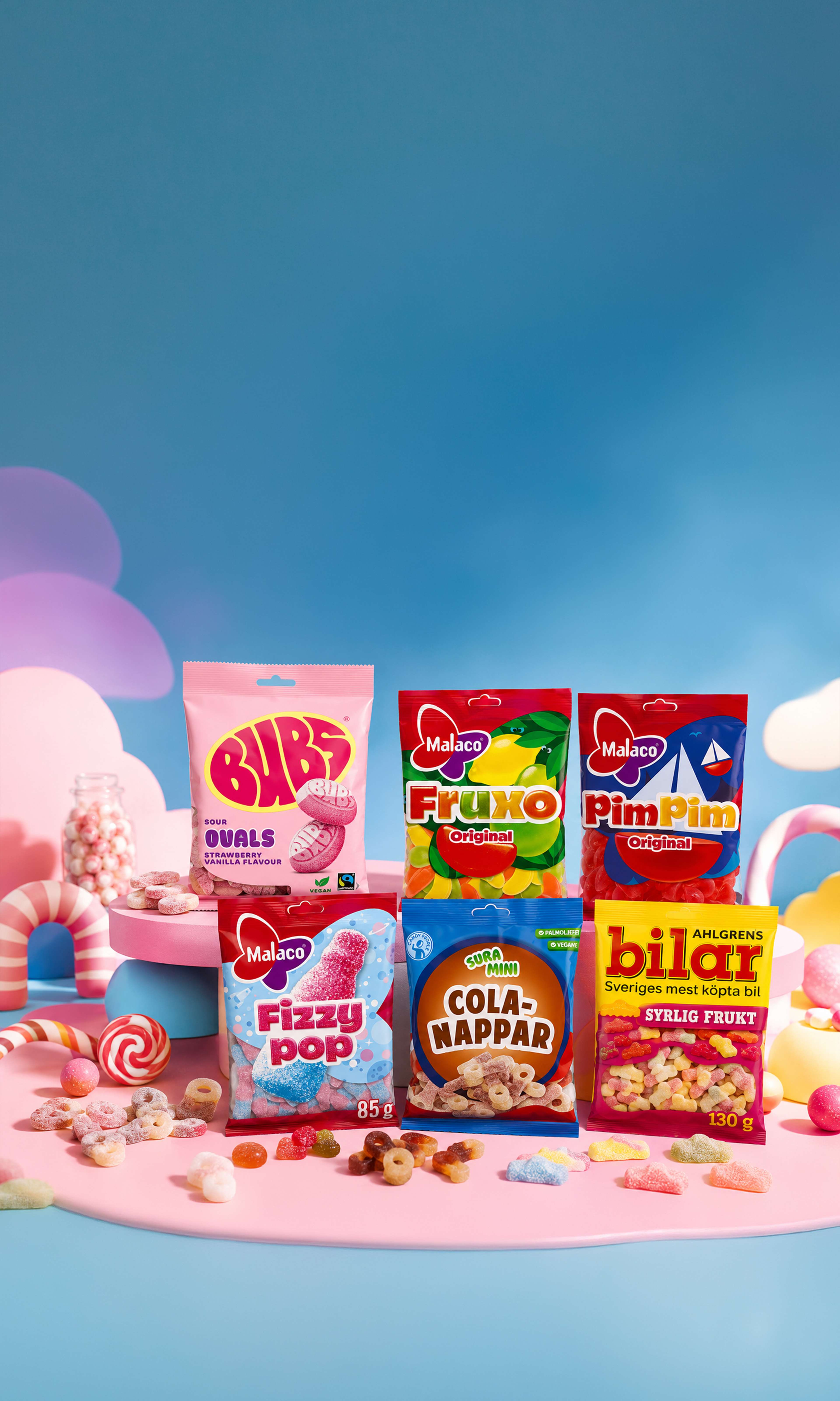 A colorful assortment of swedish candy bags displayed on a pastel pink and blue backdrop, surrounded by scattered sweets and decorative candy-themed props.