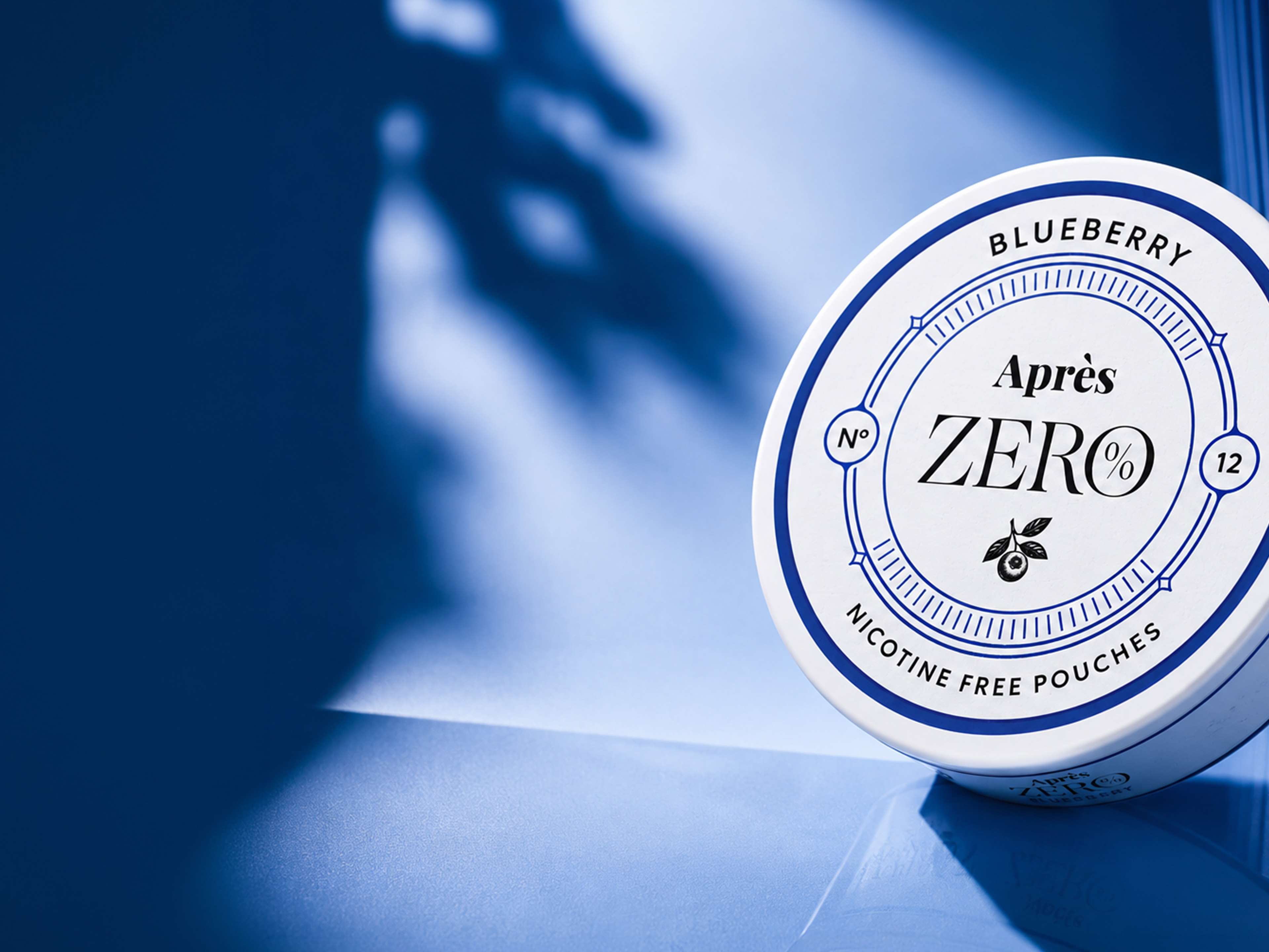 Circular tin of Après Zero blueberry nicotine-free pouches on a blue background, with shadow patterns.