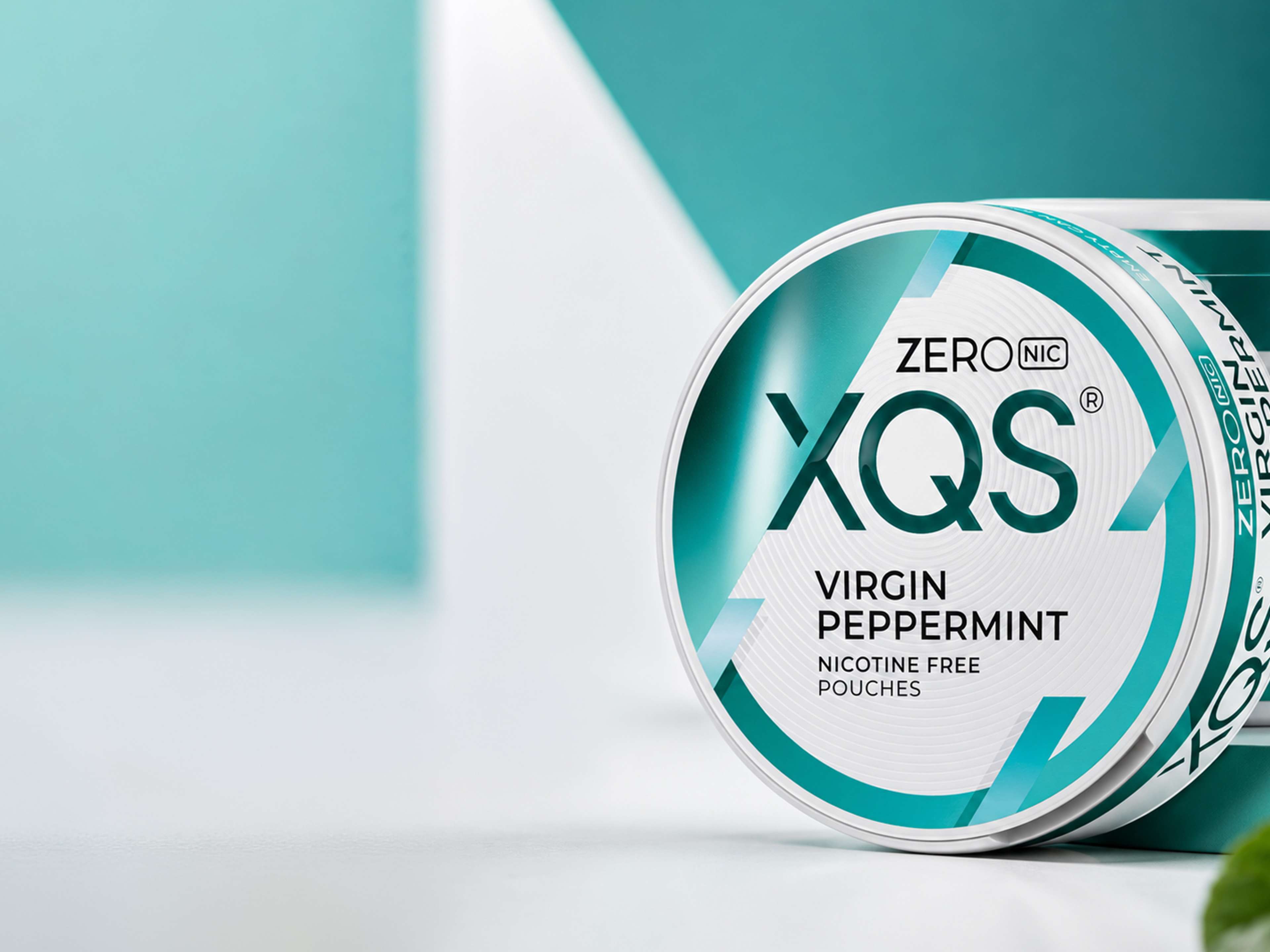 A turquoise and white container of XQS Virgin Peppermint nicotine-free pouches, labeled "ZERO NIC," with a modern geometric design background.