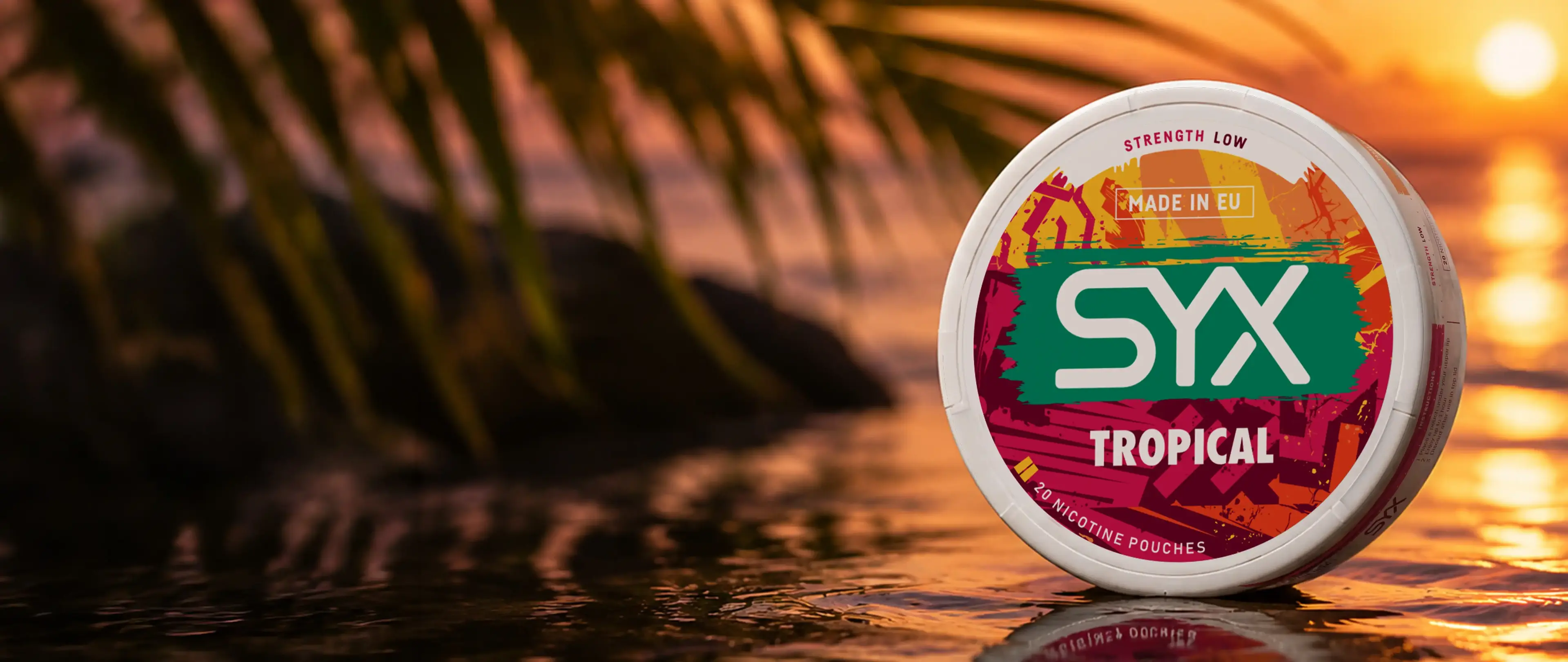 SYX Tropical nicotine pouch container on reflective surface at sunset, with palm leaves in the background.
