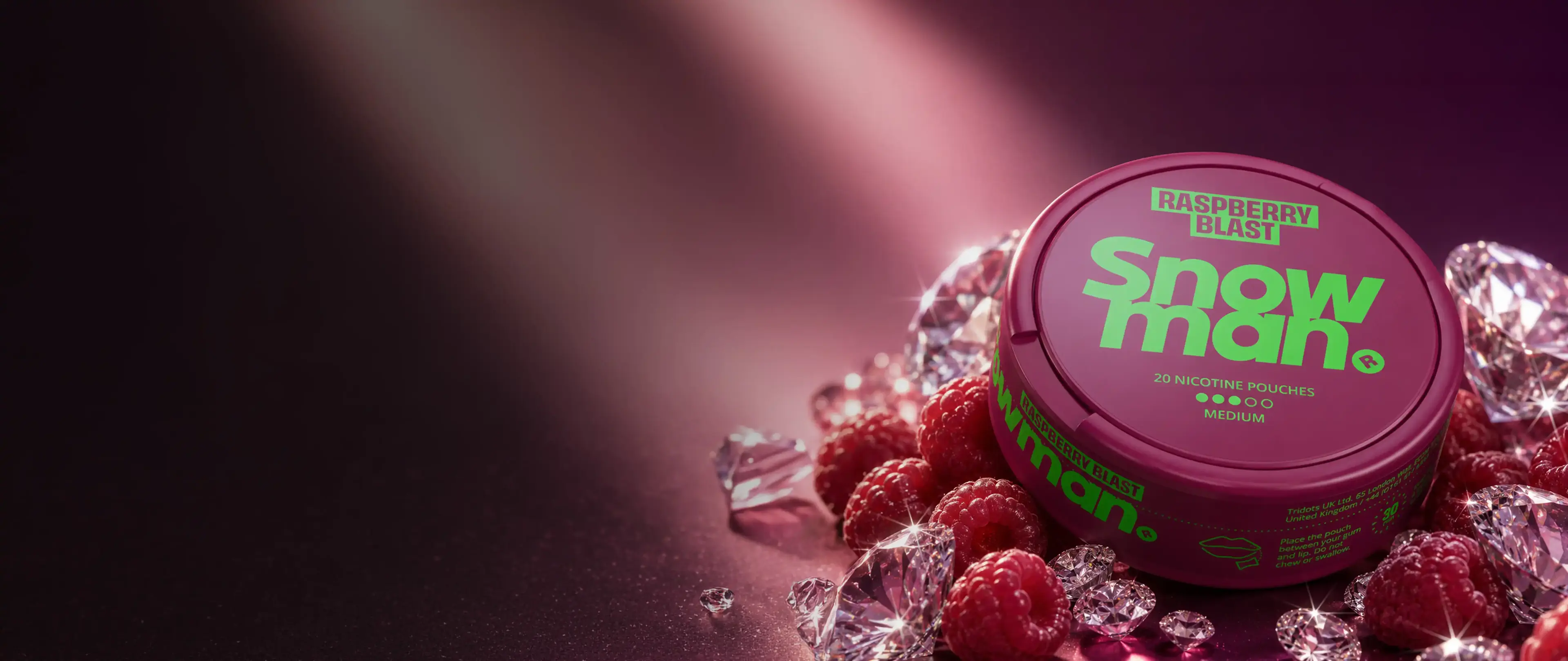 A round container of "Snowman Raspberry Blast" nicotine pouches, surrounded by raspberries and clear gemstones against a pink background.