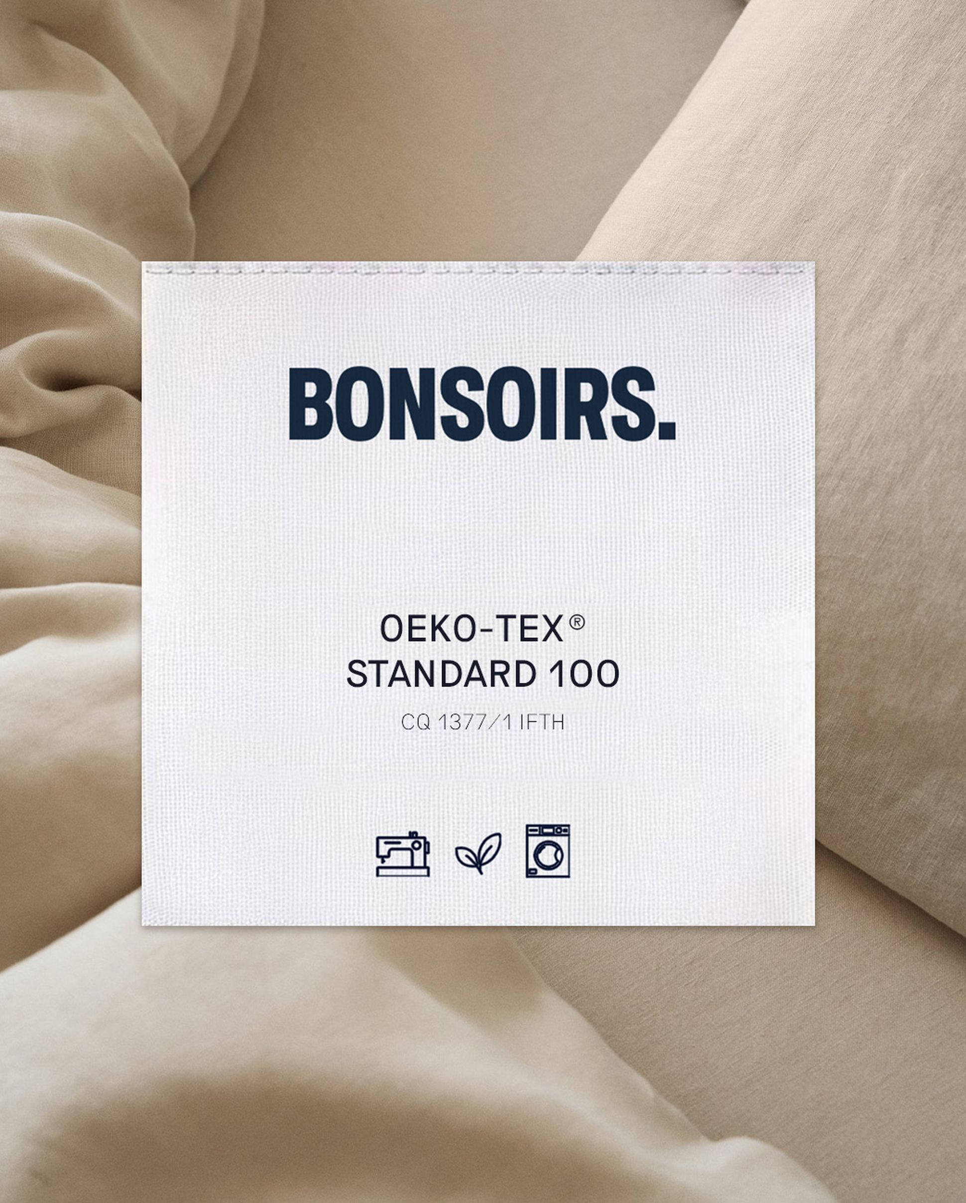 Étiquette portant la mention « BONSOIRS » sur un tissu, indiquant la certification « OEKO-TEX STANDARD 100 » avec des icônes relatives au lavage et au respect de l'environnement.