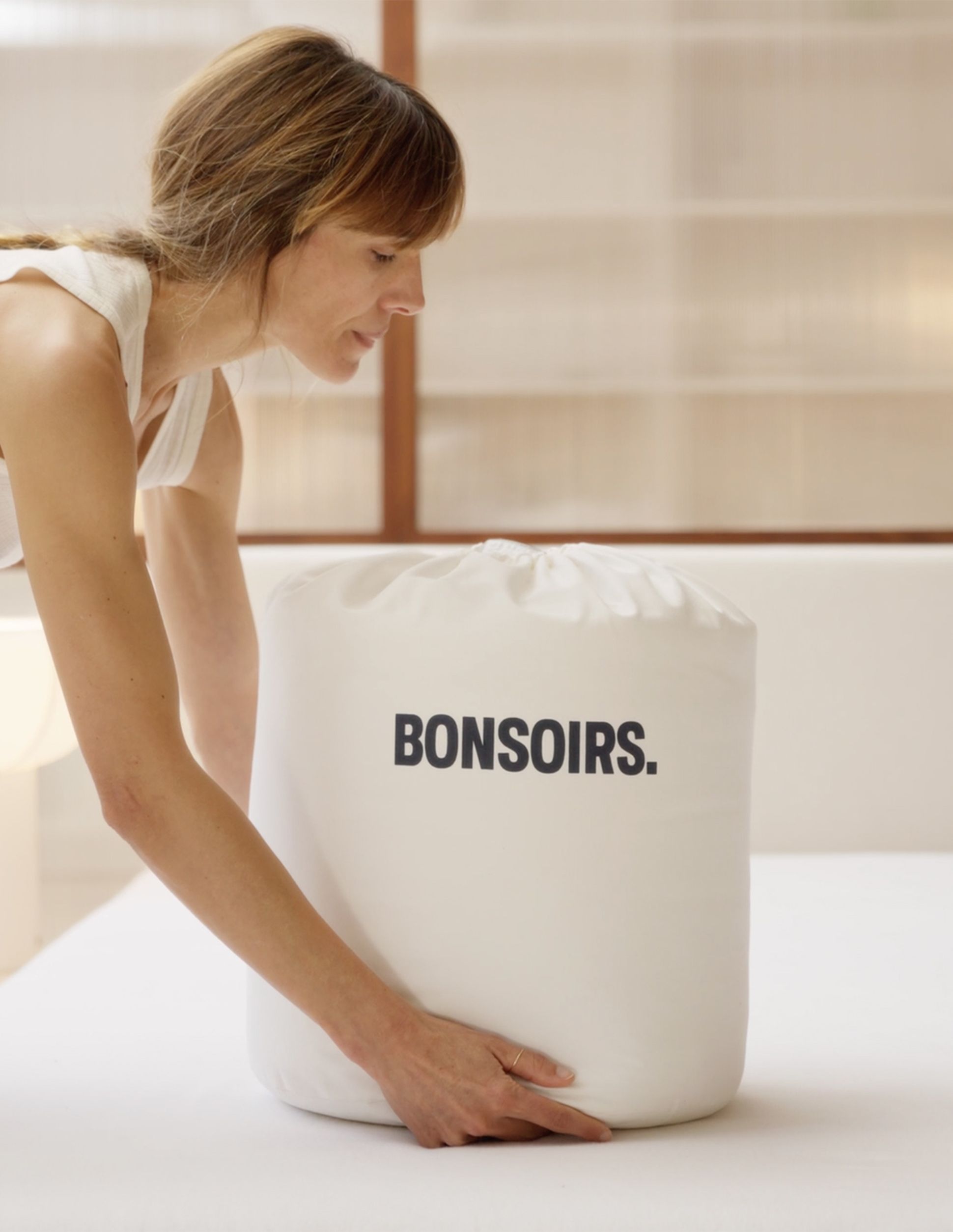 Femme qui pose un sac Bonsoirs sur un lit dans lequel il y a une couette