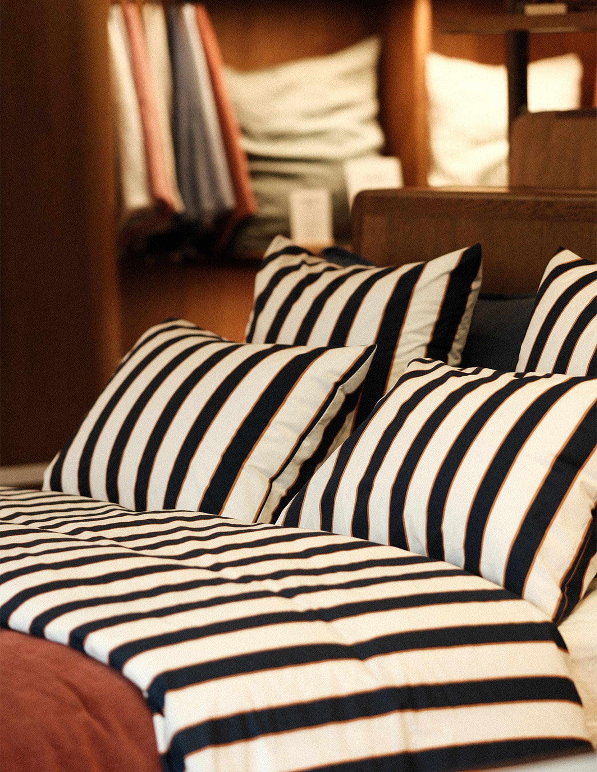 Un lit bien fait, avec des draps rayés noir et blanc et des oreillers, dans une chambre chaleureuse et bien éclairée.