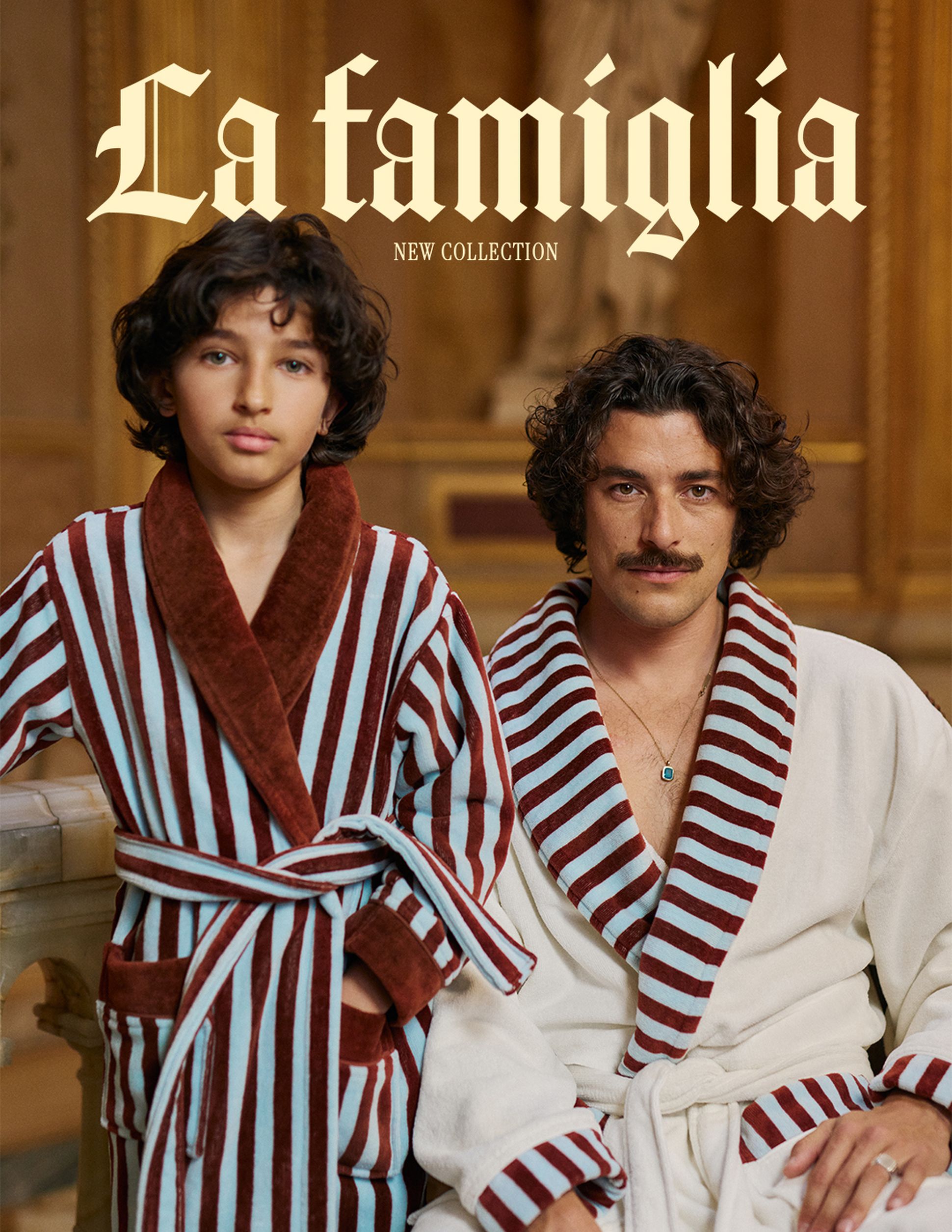 Deux personnes vêtues de peignoirs rayés, l'une de rouge et bleu, l'autre de rouge et blanc, dans un décor somptueux. Le texte « La famiglia Nouvelle Collection » figure au-dessus.