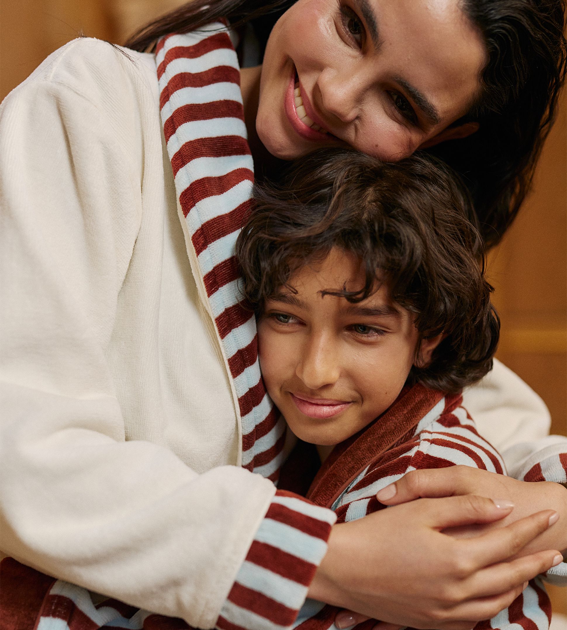 Deux personnes vêtues de peignoirs rayés s'étreignent, leurs mains visibles reposant sur un motif rayé marron et blanc.