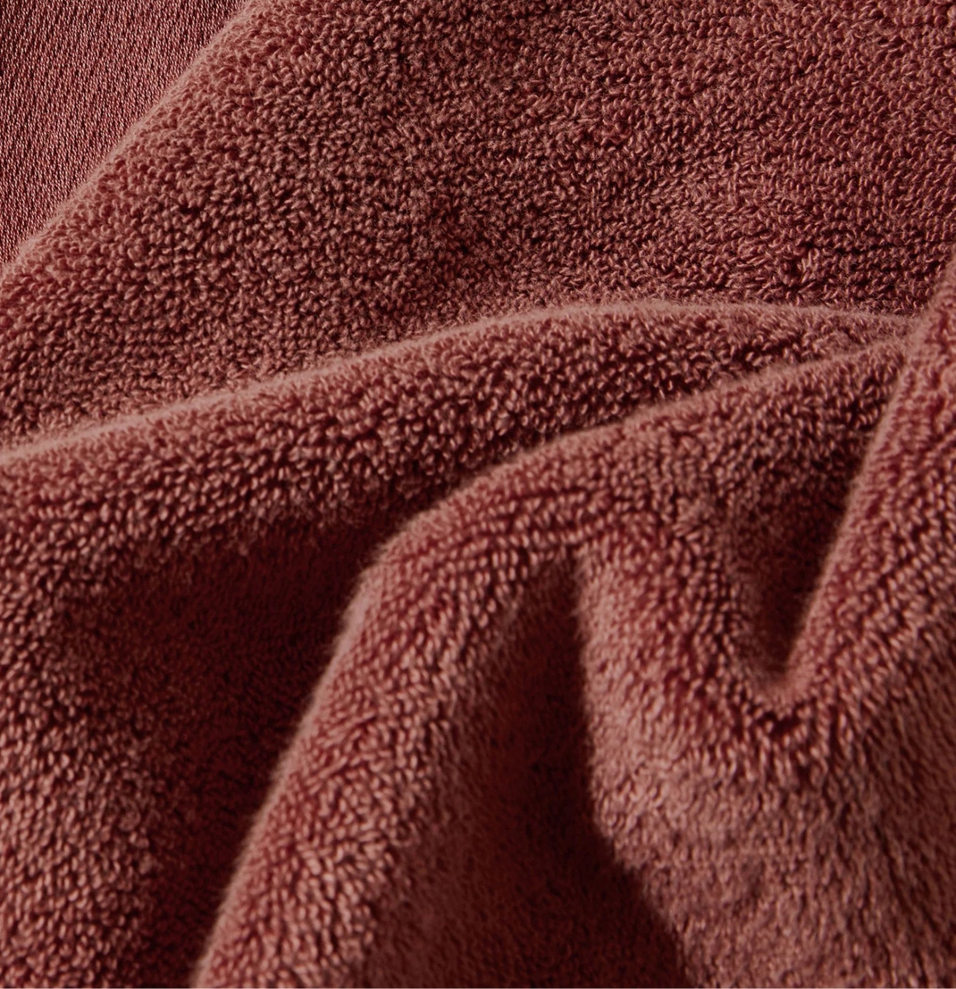 Gros plan sur un tissu brun et doux, à la surface texturée et moelleuse, mettant en valeur les plis et les ombres.