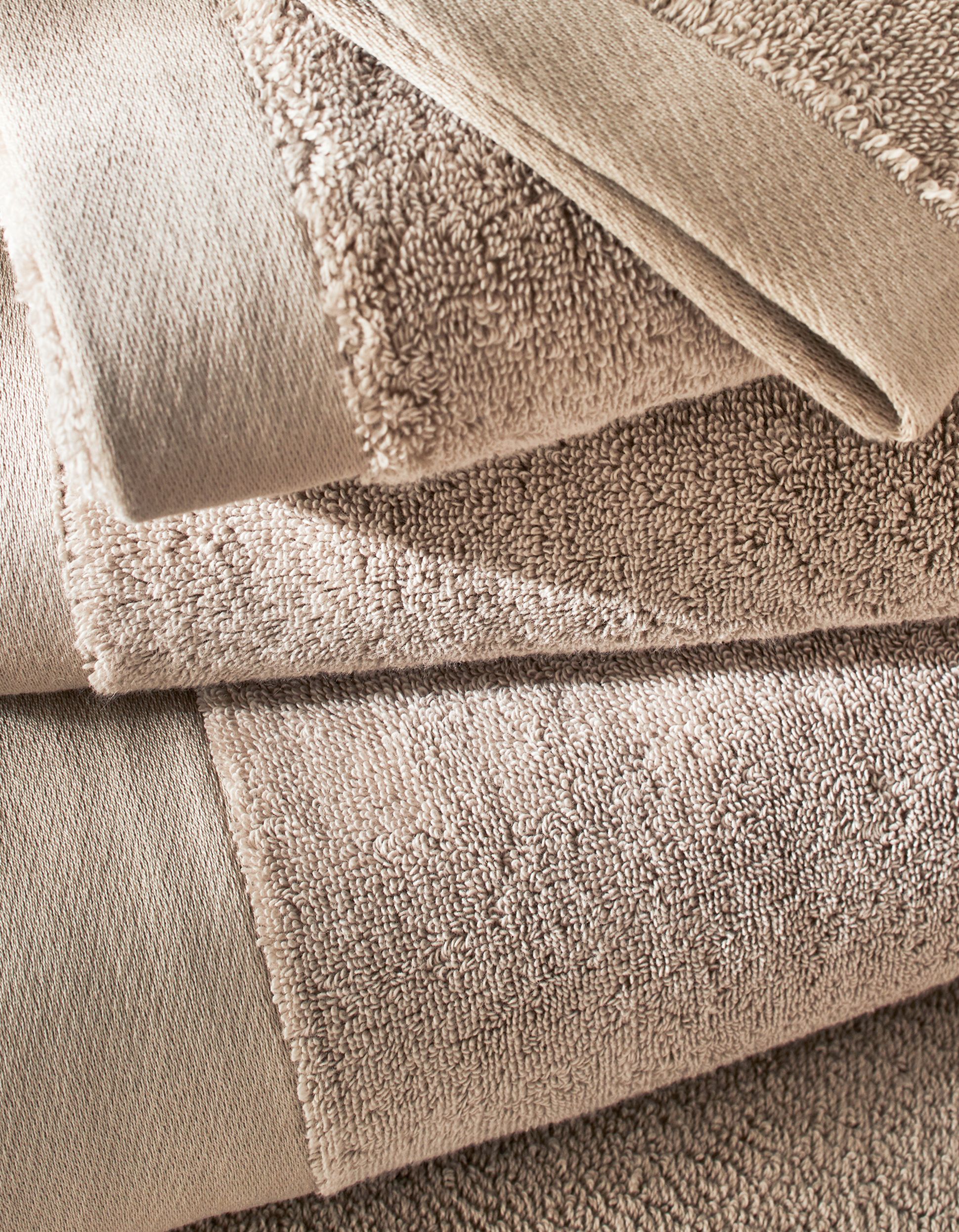 Close-up of a neatly folded stack of beige towels with visible texture and stitching details.