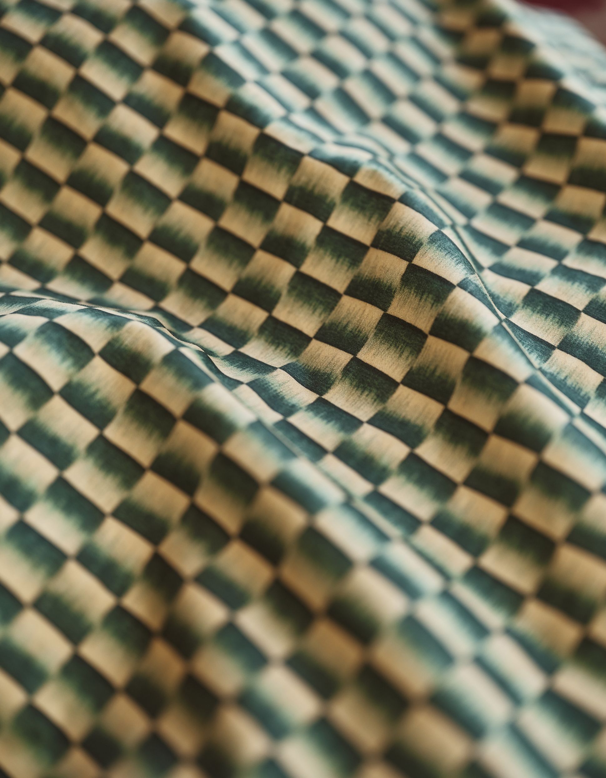 Close-up of a fabric with a wavy, geometric pattern consisting of green and beige checkerboard squares.