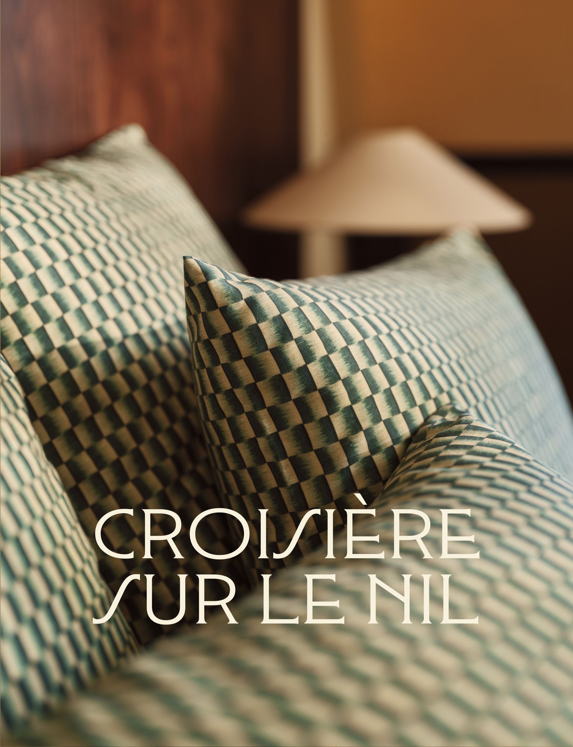 Gros plan sur des coussins à motifs, avec le texte « Along the Nile » superposé, sur un arrière-plan flou où l'on aperçoit une lampe.