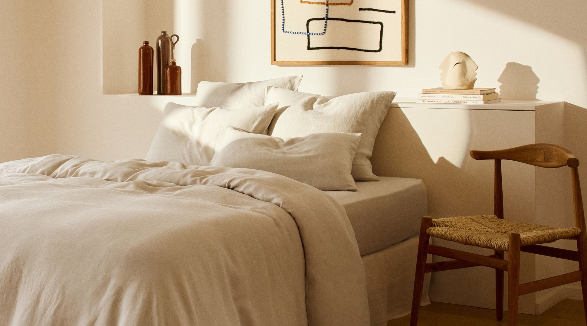 Chambre cosy avec une parure de lit en lin beige, baignée de lumière