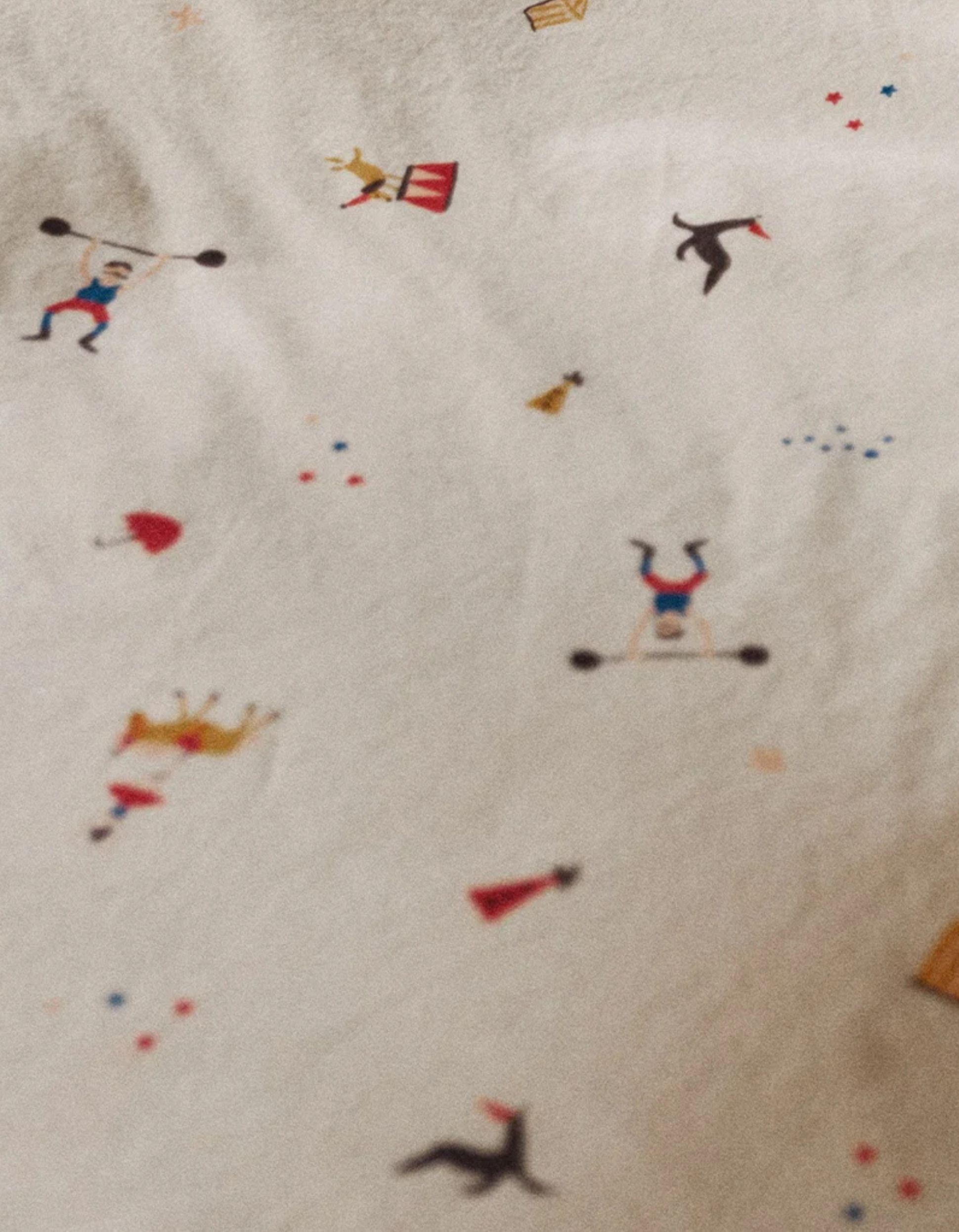 Zoom sur un lit orné d'un motif sur le thème du cirque.