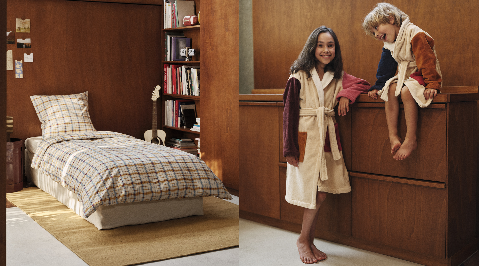 Une chambre chaleureuse avec un lit à motifs écossais, une guitare, des livres et deux enfants en peignoirs colorés, souriant près d'un meuble en bois.