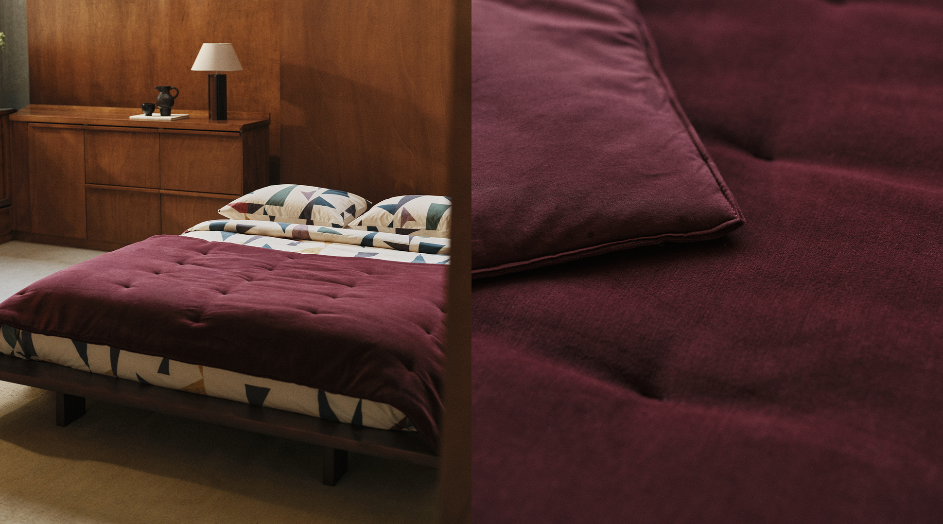 Une chambre moderne avec un lit en bois recouvert d'une couette rouge foncé et d'oreillers aux motifs géométriques. Une commode en bois sur laquelle repose une lampe se trouve à l'arrière-plan.