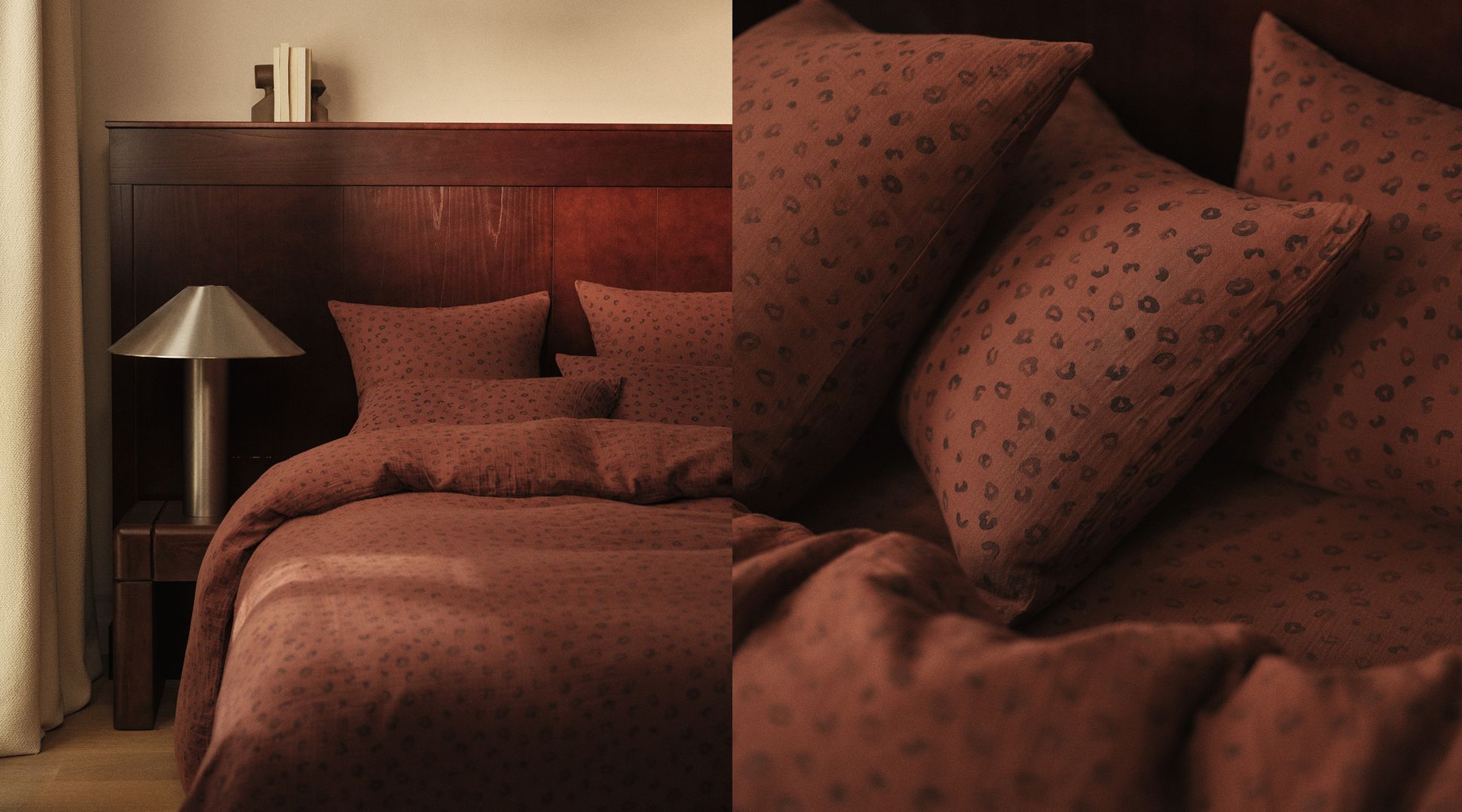 Un lit douillet avec une parure de lit rouge foncé à motifs, une tête de lit en bois et une lampe moderne posée à côté.