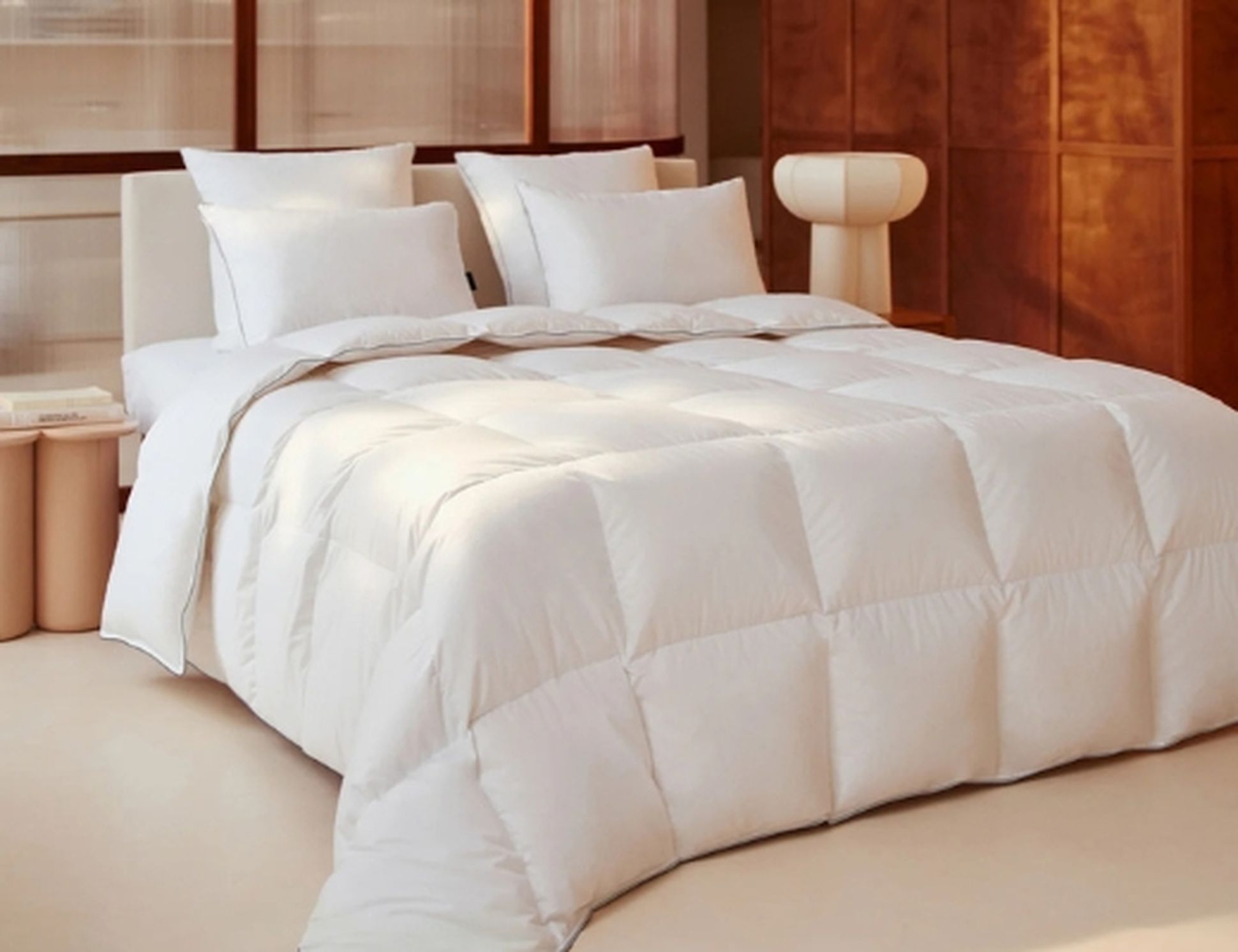 Une chambre confortable avec un lit soigneusement fait, recouvert d'une couette blanche moelleuse et d'oreillers assortis, dans un intérieur moderne à l'éclairage chaleureux.