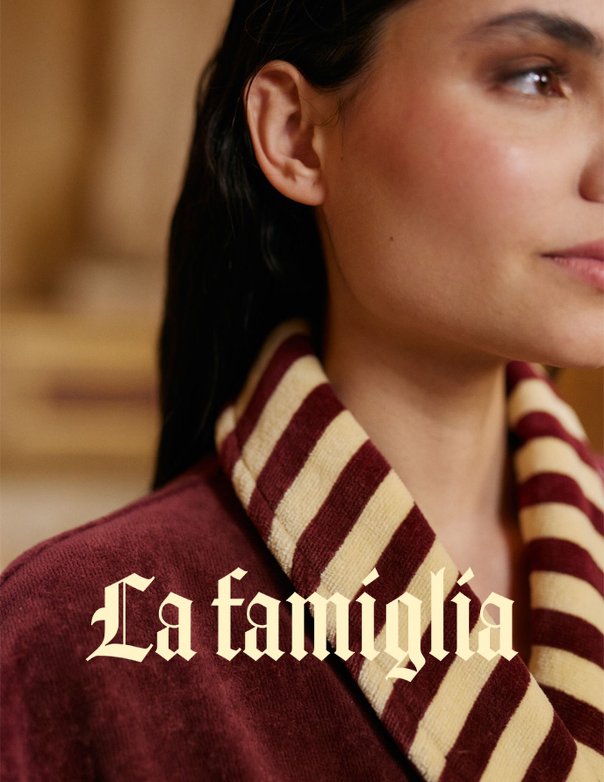 Gros plan sur une personne portant un col rayé rouge et crème, sur lequel est inscrit en lettres cursives élégantes le mot « La famiglia ».