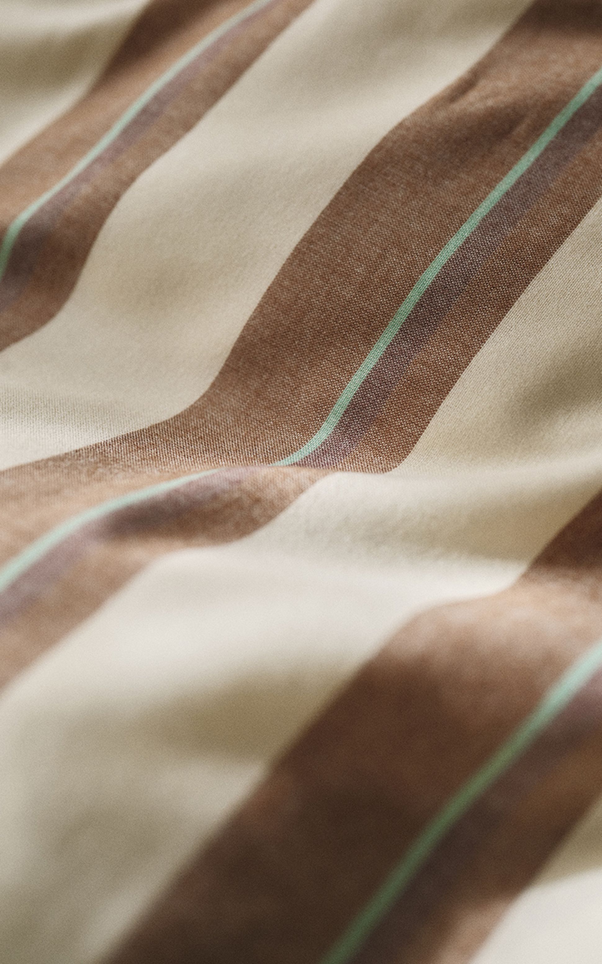 Gros plan sur un tissu à rayures verticales beiges, marron et vertes. Le tissu semble doux et présente un éclat subtil.