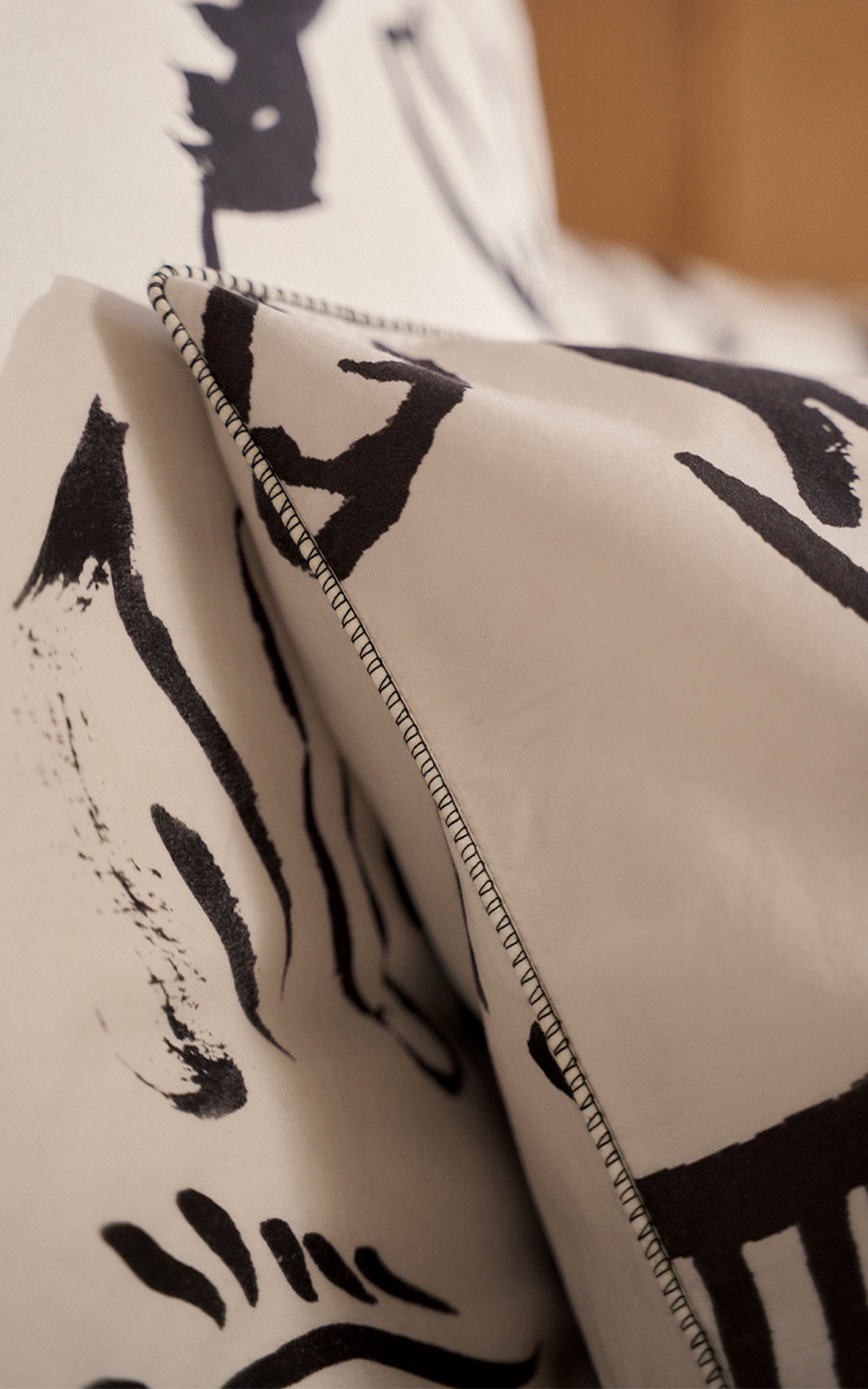 Gros plan sur un tissu beige avec des motifs abstraits noirs et des bords cousus.